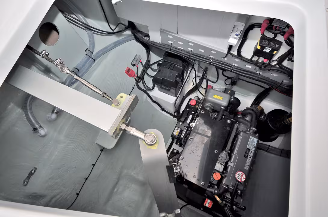A powerful engine neatly installed in a clear and clean engine compartment (gray topcoat). Note the inter-rudder linking rod and the steering adjustments
