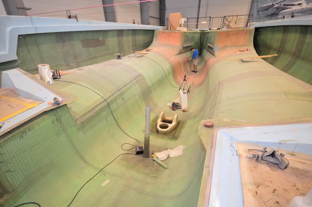 A Neel 51 at the end of the composite infusion phase. The mold in 3 parts includes the central hull and the inner half-hulls.  The outer half-hulls can be seen, before the "structural box" is closed by the installation of the deck and the coachroof (by ha